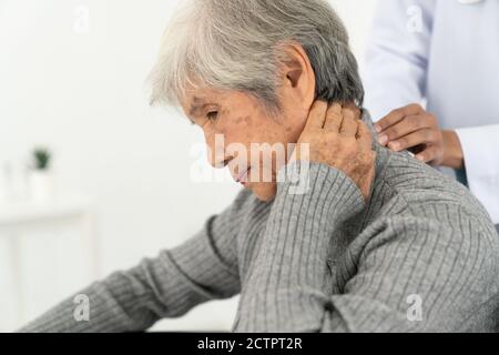Donna anziana con dolore al collo nell'ufficio medico, donna anziana malata con dolore al collo e alle spalle alle articolazioni e ai muscoli. Foto Stock