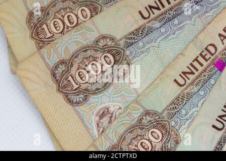 La moneta degli Emirati Arabi Uniti (EAU) - Mille Dirham note sparse su uno sfondo bianco. Lo scambio di denaro. Foto Stock