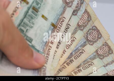 Persone dando a mano la moneta degli Emirati Arabi Uniti (EAU) - Mille Dirham note sparse su uno sfondo bianco. Lo scambio di denaro. Foto Stock