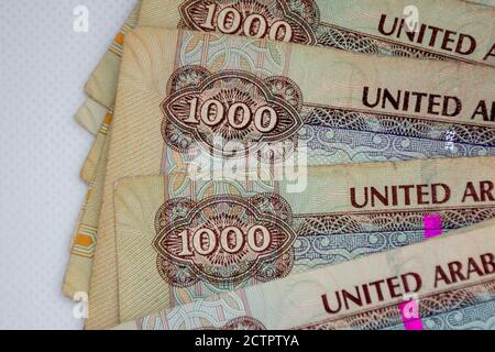 La moneta degli Emirati Arabi Uniti (EAU) - Mille Dirham note sparse su uno sfondo bianco. Lo scambio di denaro. Foto Stock