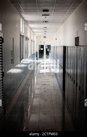 Corridoio vuoto di una scuola superiore o di un'università chiuso durante il COVID-19 (Coronavirus). Gli armadietti si sono sbavati nel corridoio solitario. Foto Stock