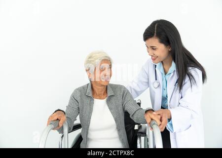 Fisioterapista che guarda un paziente senior seduto in sedia a rotelle, in un medico e in un paziente su sedia a rotelle Foto Stock