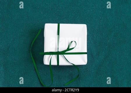 Regalo in un pacchetto bianco su sfondo verde. Foto Stock