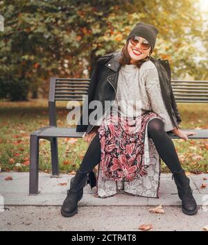 Sinceramente ridendo donna vestito stile boho colorato abito lungo, caldo maglia maglione con una giacca biker in pelle nera Foto Stock