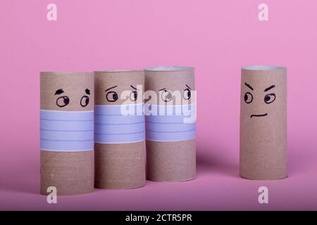 quattro rotoli di carta igienica vuoti, tre con maschera facciale che guarda ad uno senza protezione della bocca, sfondo rosa Foto Stock