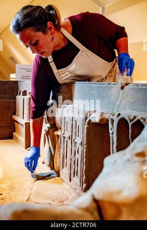 Un dipendente che lavora sul sarcofago durante il restauro.UN sarcofago romano rotto al Museo Nazionale delle Antichità di Leida è in fase di restauro. La scatola di pietra arenaria di 2.5 metri è stata trovata nel 1930 a Simpelveld in Limburgo. Precedenti ricerche sul materiale osseo hanno stabilito che la donna cremata aveva tra i 35 e i 50 anni quando morì e aveva vissuto una buona vita senza duro lavoro. Foto Stock