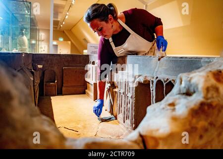 Un dipendente che lavora sul sarcofago durante il restauro.UN sarcofago romano rotto al Museo Nazionale delle Antichità di Leida è in fase di restauro. La scatola di pietra arenaria di 2.5 metri è stata trovata nel 1930 a Simpelveld in Limburgo. Precedenti ricerche sul materiale osseo hanno stabilito che la donna cremata aveva tra i 35 e i 50 anni quando morì e aveva vissuto una buona vita senza duro lavoro. Foto Stock