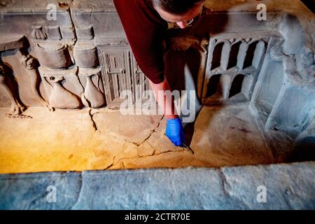 Un dipendente che lavora sul sarcofago durante il restauro.UN sarcofago romano rotto al Museo Nazionale delle Antichità di Leida è in fase di restauro. La scatola di pietra arenaria di 2.5 metri è stata trovata nel 1930 a Simpelveld in Limburgo. Precedenti ricerche sul materiale osseo hanno stabilito che la donna cremata aveva tra i 35 e i 50 anni quando morì e aveva vissuto una buona vita senza duro lavoro. Foto Stock