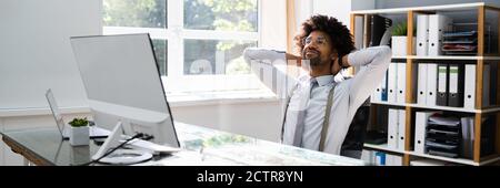 Uomo d’affari africano di successo che si appoggia indietro. Dipendente felice Foto Stock