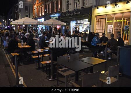 I bevitori di tarda notte a Soho, Londra, come da oggi i pub e i ristoranti saranno soggetti a un coprifuoco alle 22:00 per combattere l'aumento dei casi di coronavirus in Inghilterra. Foto Stock