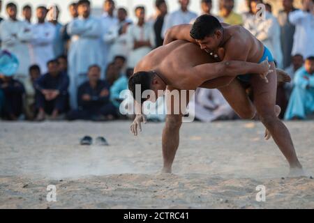 Il lottatore di Kushti si ribalta un altro durante la loro competizione su un lotto vacante a Dubai, Emirati Arabi Uniti (Emirati Arabi Uniti) Foto Stock