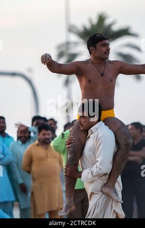 Il lottatore di Kushti in shorts gialli celebra la vittoria cavalcando sulle spalle di uno dei suoi sostenitori a Dubai, Emirati Arabi Uniti Foto Stock