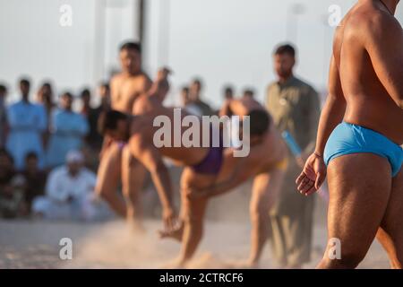 Kushti wrestler in pantaloncini blu attende il suo turno per competere con i colleghi addetti alle importazioni a Dubai, Emirati Arabi Uniti (Emirati Arabi Uniti) Foto Stock