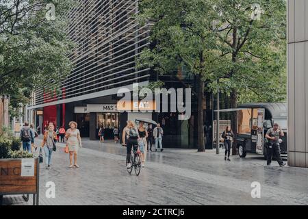Londra, UK - 24 agosto 2020: Pedoni e ciclista su più Londra, una parte della zona di London Bridge City che include il Municipio, la Scoop amphi Foto Stock