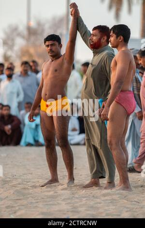 Giudice alza la mano di un lottatore quando annuncia i concorrenti nel prossimo incontro di Kushti Wrestling a Dubai, Emirati Arabi Uniti (Emirati Arabi Uniti) Foto Stock