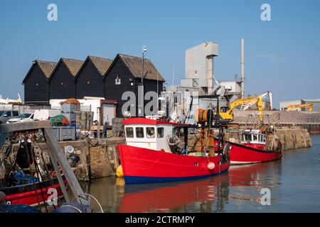 Barche da pesca nel molo di fronte a capannoni in legno dipinto di nero a Whistable, Kent, Regno Unito Foto Stock