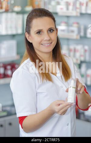 farmacista femminile che suggerisce utili prodotti per la cura del corpo in farmacia Foto Stock