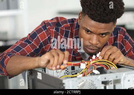 tecnico informatico che esamina i cavi del pc Foto Stock