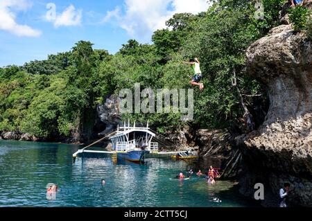Saltando da una scogliera verso il mare Foto Stock
