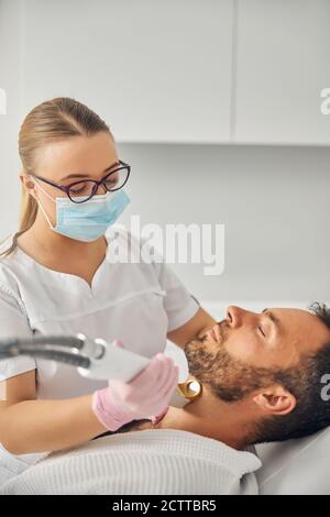 Donna estetista che esegue la procedura di rimozione dei capelli laser Foto Stock