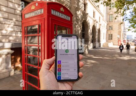 Londra, Regno Unito. 24 Settembre 2020. Foto scattata il 24 settembre 2020 mostra l'app NHS COVID-19 visualizzata su un telefono di fronte a una scatola telefonica rossa a Londra, Gran Bretagna. Giovedì, più di un milione di persone hanno scaricato l'app NHS COVID-19 per il tracciamento dei contatti, da lungo tempo attesa dal governo britannico, per l'Inghilterra e il Galles entro il suo primo giorno di lancio. L'app ufficiale NHS COVID-19 istruisce gli utenti a mettere in quarantena per 14 giorni se rileva che erano vicini a qualcuno che ha il virus. Credit: Tim Ireland/Xinhua/Alamy Live News Foto Stock