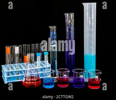 Vetreria chimica da laboratorio con vari liquidi colorati sul tavolo. Provette con liquidi colorati nel supporto sul tavolo in laboratorio. Foto Stock