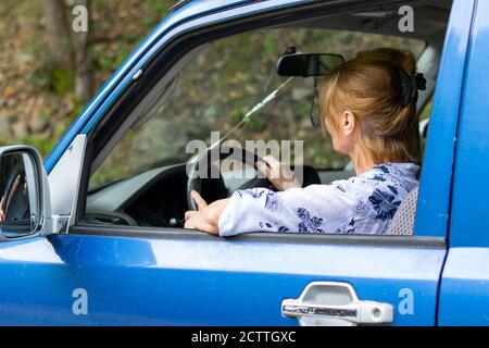 La signora anziana guida l'auto all'aperto Foto Stock