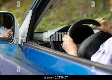 La signora anziana guida l'auto all'aperto Foto Stock