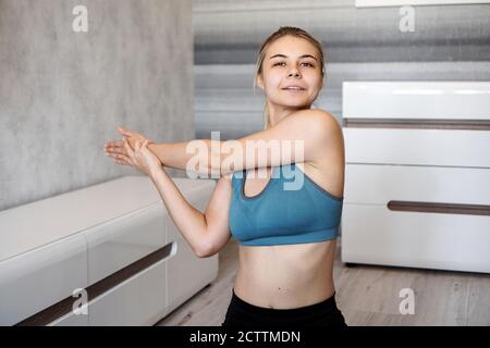 Concetto di fitness, casa e dieta. Ragazza sorridente che strisciava sul pavimento a casa. Allungare le braccia e le spalle Foto Stock