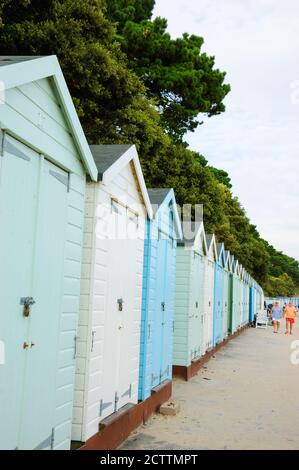 MUDEFORD, INGHILTERRA, Regno Unito - 26 AGOSTO 2017: Coppia anziana che cammina ad Avon Beach con le sue pittoresche capanne in legno alla sera. Foto Stock