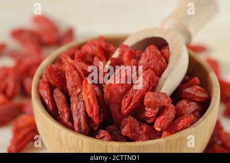 Primo piano di bacche di goji essiccate con cucchiaio in recipiente di legno Foto Stock