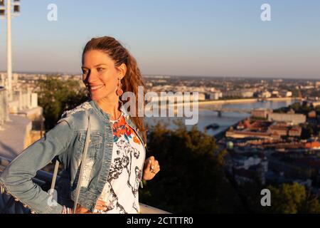 Giovane donna urbana equilibrata che guarda via nel tramonto della città Foto Stock