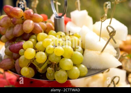 Uva e fette di melone succoso maturo su un piatto Foto Stock