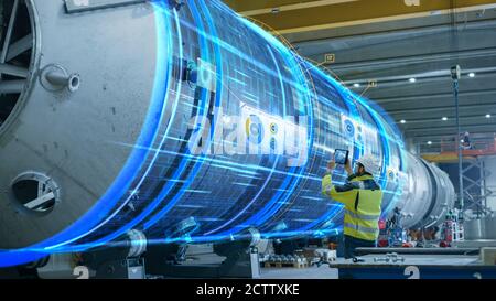 Concetto AR: L'ingegnere industriale utilizza il tablet digitale con realtà aumentata per eseguire la scansione di grandi costruzioni metalliche, visualizzazione di spettacoli con effetti speciali Foto Stock