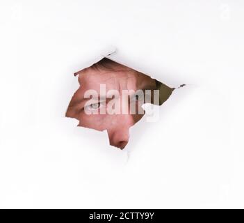 Un uomo guarda attraverso un foro nella carta Foto Stock