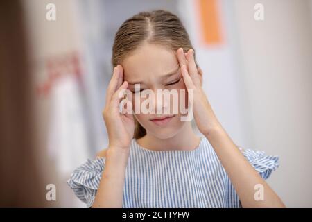 Ragazza che ha un mal di testa e che guarda infelice Foto Stock