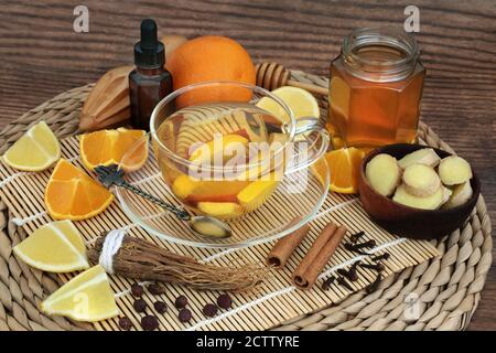 Rimedio naturale alle erbe per il virus del raffreddore e dell'influenza con bevanda calda con frutta, erbe, miele, spezie e olio essenziale. Foto Stock