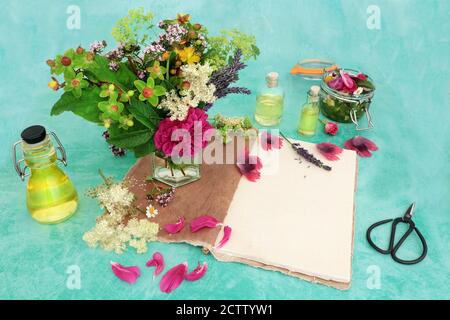 Preparazione di medicina di erbe con erbe e fiori utilizzati nella produzione di oli essenziali aromaterapia con taccuino di canapa e bottiglie di olio. Assistenza sanitaria naturale. Foto Stock