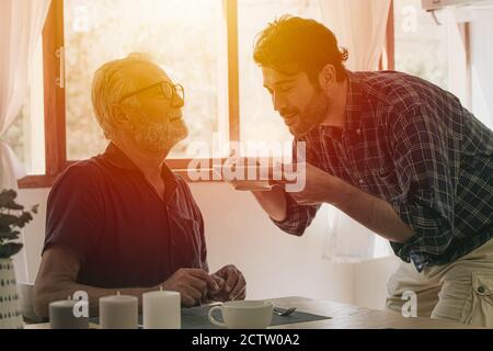 Felice anziano anziano uomo godere di cucina con la famiglia al cucina soggiorno home attività di svago e la gente stile di vita Foto Stock