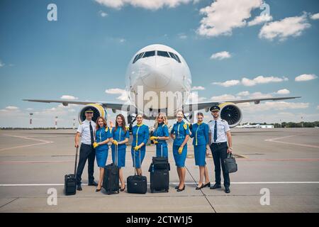 Lavoratori di linea aerea con valigie di viaggio in piedi all'aperto in campo aereo Foto Stock