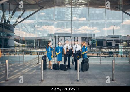 Lavoratori delle compagnie aeree con valigie di viaggio in piedi per strada Foto Stock