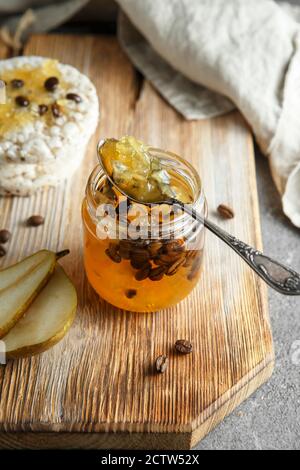 marmellata di pere con chicchi di caffè. Vasetto di marmellata di pere su tavola di servizio in legno su sfondo grigio di cemento Foto Stock