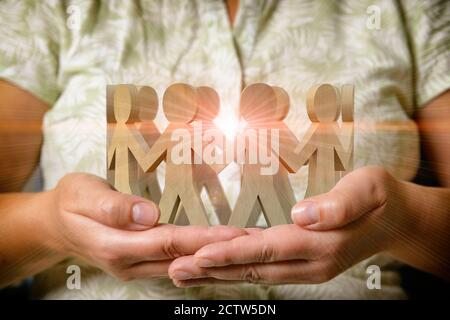 Figure in legno di persone in cerchio che tengono le mani e si levano in piedi sulle mani di una donna. Il concetto di una rete sociale, di un'impresa o di altre relazioni. Foto Stock