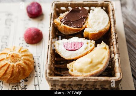 Profiteroles fatti in casa sul foglio di musica con note. Profiteroles (choux à la crème) - polpette di pasta di choux francese farcite con crema pasticcera o formaggio di cottage Foto Stock