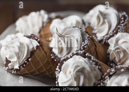 Un sacco di coni gelato su tavolo di legno. Gelati morbidi o crema surgelata in coni. Waffle marshmallow imitando gelato Foto Stock