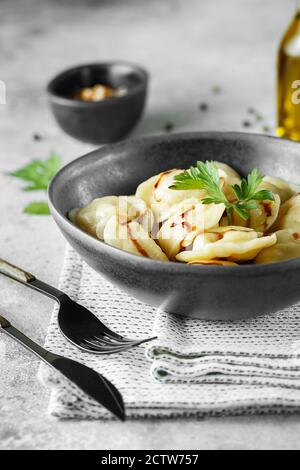 Gnocchi di carne - pelmeni russi, ravioli con carne su una ciotola grigia. Fotografia alimentare Foto Stock