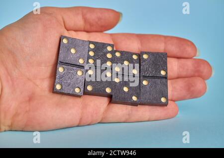 La mano di una donna contiene quattro pezzi del gioco da tavolo Domino. Primo piano Foto Stock