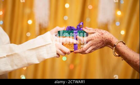 Primo piano di mani di Fratello che danno dono alla sorella durante il raksha Bandhan, Bhai Dooj o Bhaubeej festival religioso indiano Foto Stock