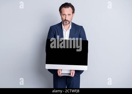 Foto di dispiaciuto sconvolto anziano uomo d'affari maturo tenere computer schermo monitor vogliono acquistare costosi gadget non hanno soldi poveri il lavoratore indossa un abito blu Foto Stock