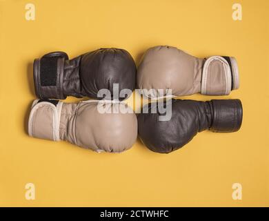 I guanti da combattimento neri e beige per l'allenamento sportivo si trovano su un superficie gialla Foto Stock